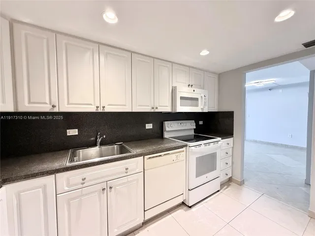 a kitchen with white cabinets and white appliances