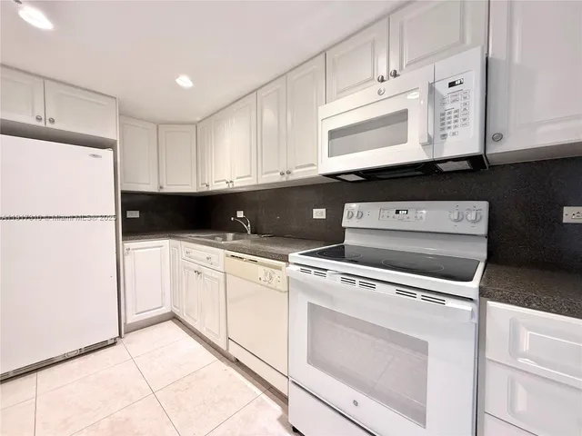 a kitchen with a refrigerator a stove top oven and cabinets