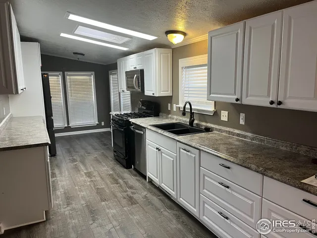 a large kitchen with granite countertop a sink and white cabinets