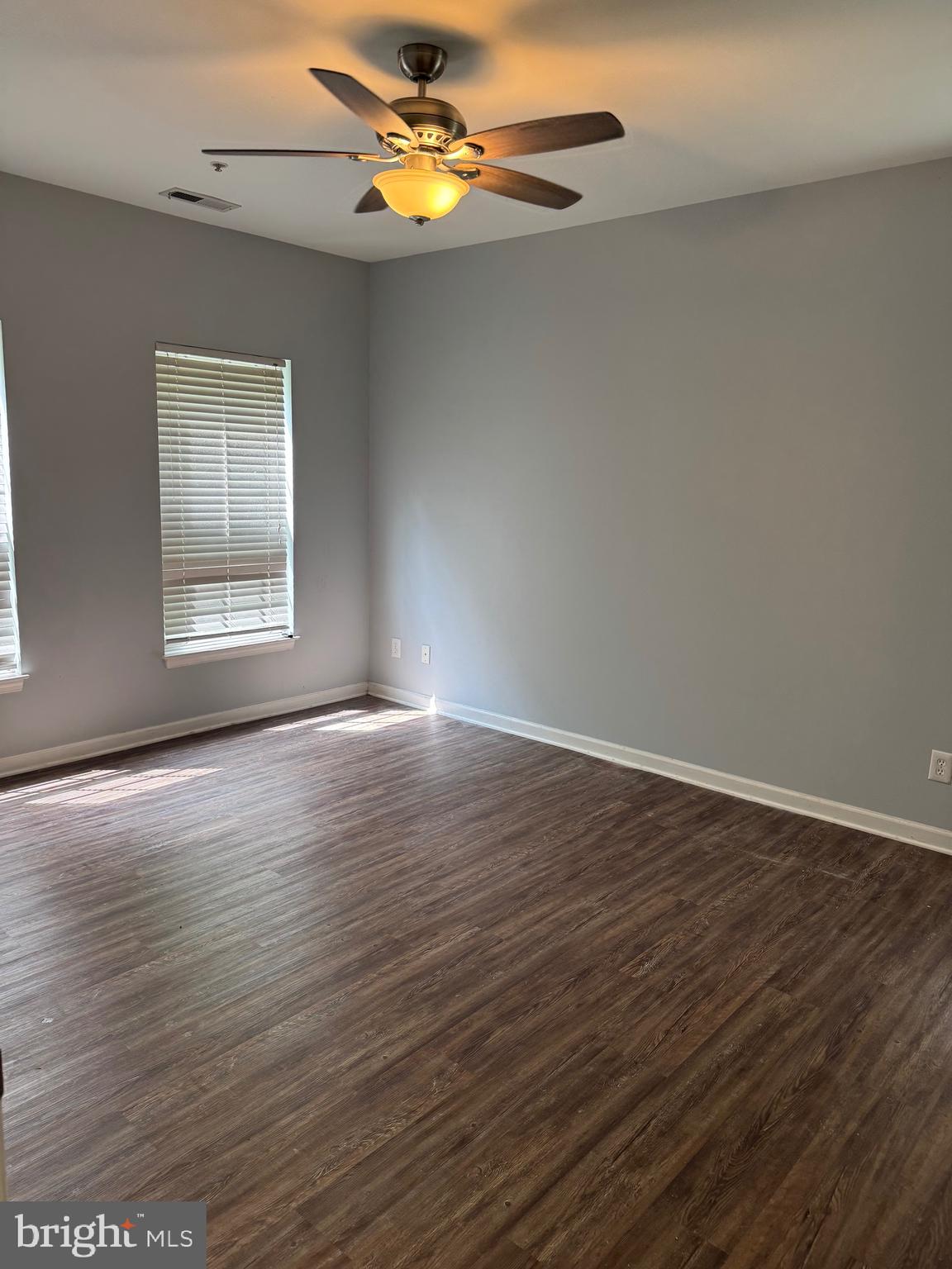 2003 Whispering Ponds Court, Unit 1C Salisbury, MD 21804 - Photo 6 of 12 an empty room with wooden floor chandelier fan and windows