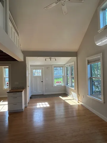 a view of an empty room with window and wooden floor