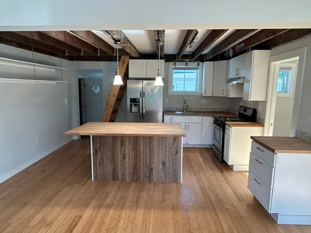 a kitchen with a wooden floor and chairs