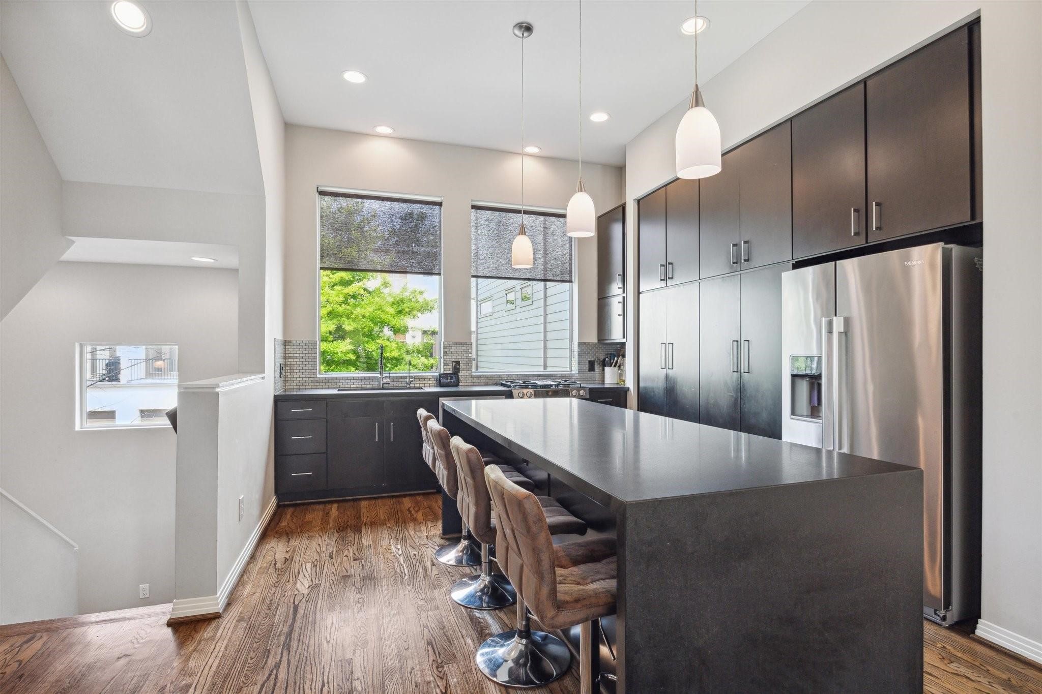 1630 Dennis Street Houston, TX 77004 - Photo 15 of 33 a kitchen with stainless steel appliances kitchen island granite countertop a refrigerator a sink and wooden cabinets