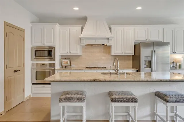 a kitchen with stainless steel appliances granite countertop a refrigerator and a stove top oven