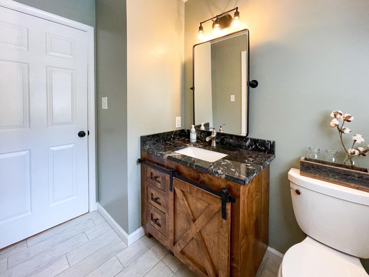 4512 Roaring Run Road Goode, VA 24556 - Photo 23 of 54 a bathroom with a granite countertop toilet sink and mirror