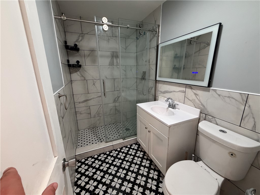 302 Sirrine Street Honea Path, SC 29654 - Photo 17 of 24 A well-appointed bathroom features a glass-enclosed shower, stylish vanity, and geometric patterned floor tiling.