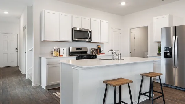 a kitchen with stainless steel appliances white cabinets and chairs