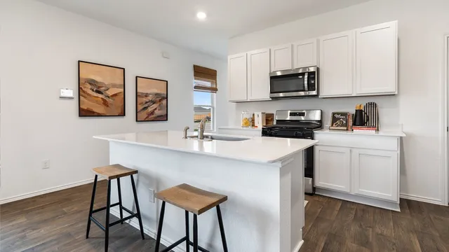 a kitchen with stainless steel appliances kitchen island granite countertop a sink a stove a refrigerator and a dining table with wooden floor