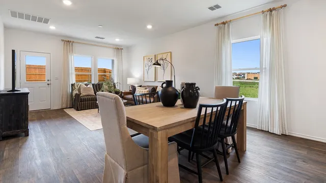 a kitchen with stainless steel appliances granite countertop a dining table chairs and a refrigerator