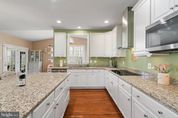 a large kitchen with granite countertop a large counter top appliances and cabinets