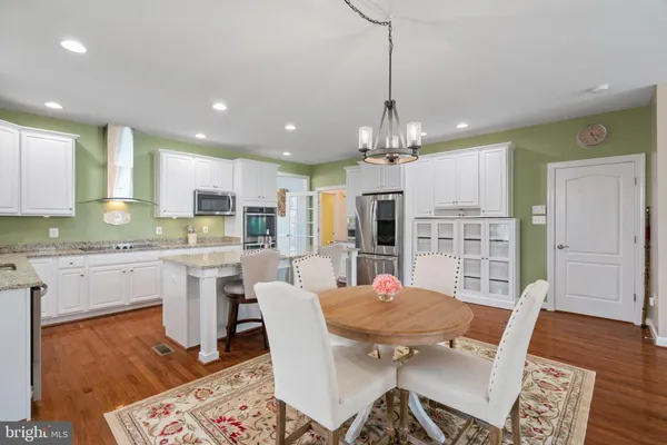 a open kitchen with stainless steel appliances granite countertop a dining table chairs and granite counter tops