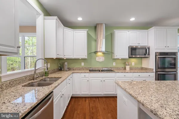 a kitchen with stainless steel appliances granite countertop a sink a stove and a microwave