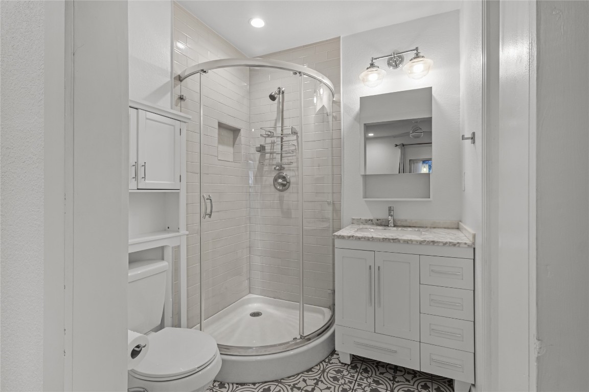 713 East 45th Street Austin, TX 78751 - Photo 22 of 28 a bathroom with a granite countertop sink toilet a shower and a mirror