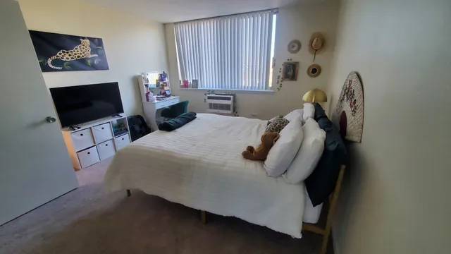 a bedroom with a bed and flat tv screen on the dresser