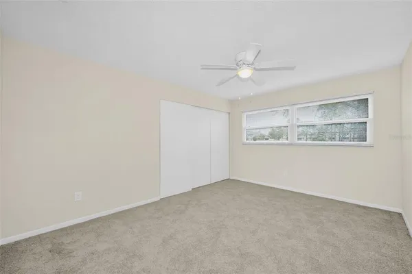 an empty room with a window and a ceiling fan