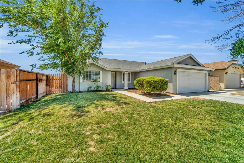 a view of a house with a yard and a large tree