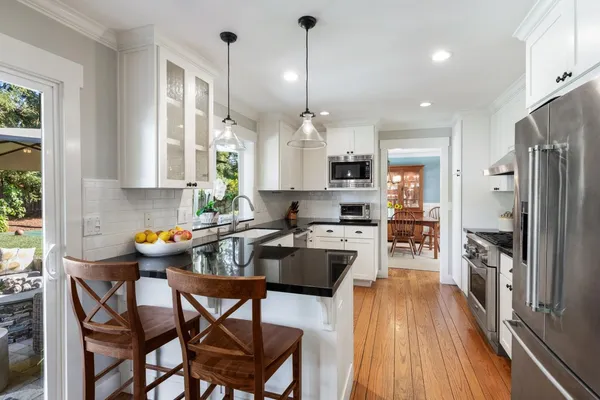 a kitchen with refrigerator a stove and chairs with wooden floor