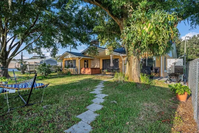 a view of house with a big yard and large trees