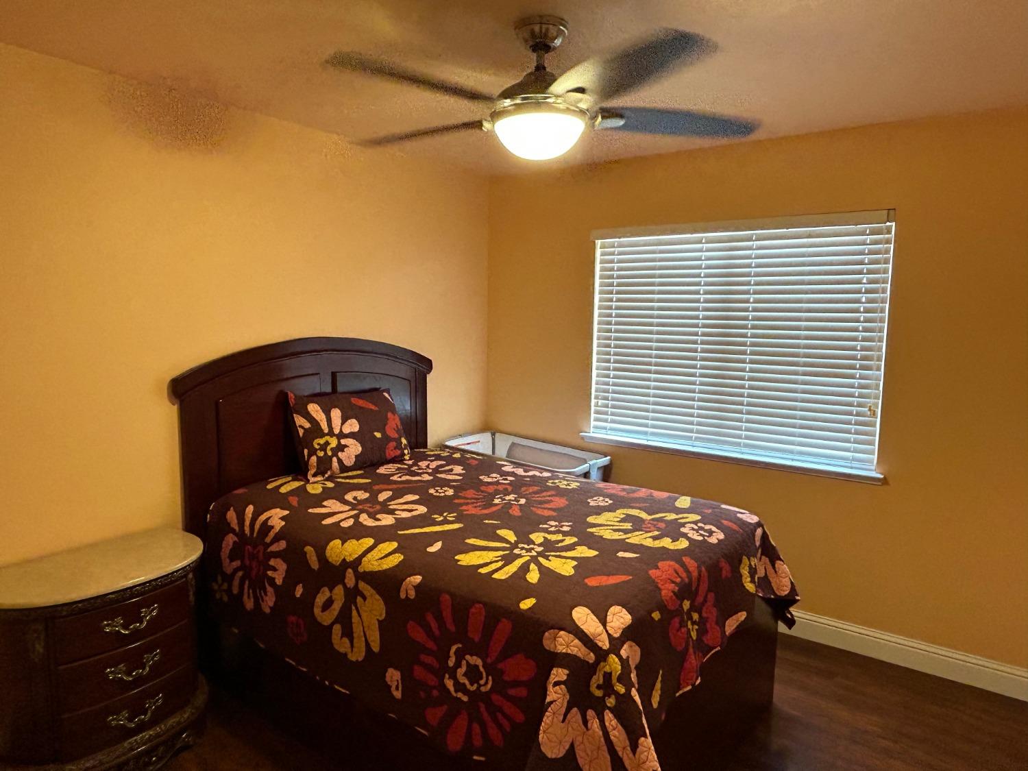 14039 West F Street Kerman, CA 93630 - Photo 11 of 19 a bedroom with a bed and a chandelier