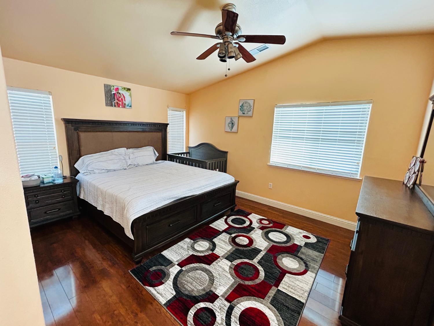 14039 West F Street Kerman, CA 93630 - Photo 14 of 19 a bedroom with a bed a dresser with wooden floor