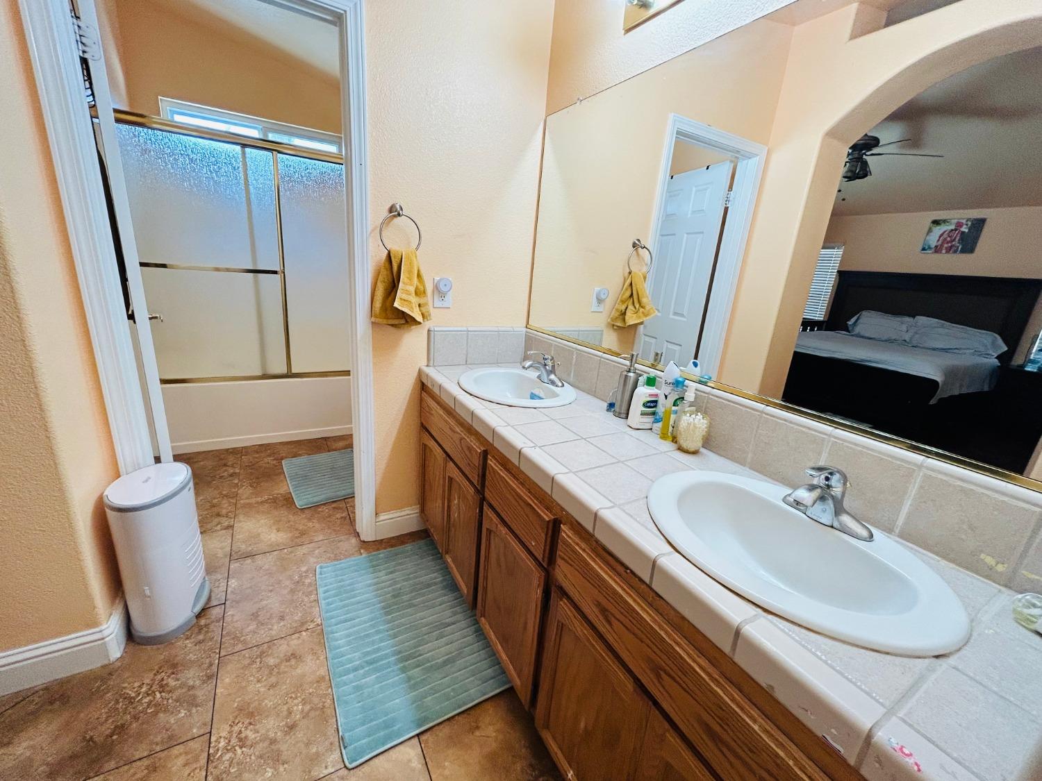 14039 West F Street Kerman, CA 93630 - Photo 15 of 19 a bathroom with a sink a toilet and a mirror