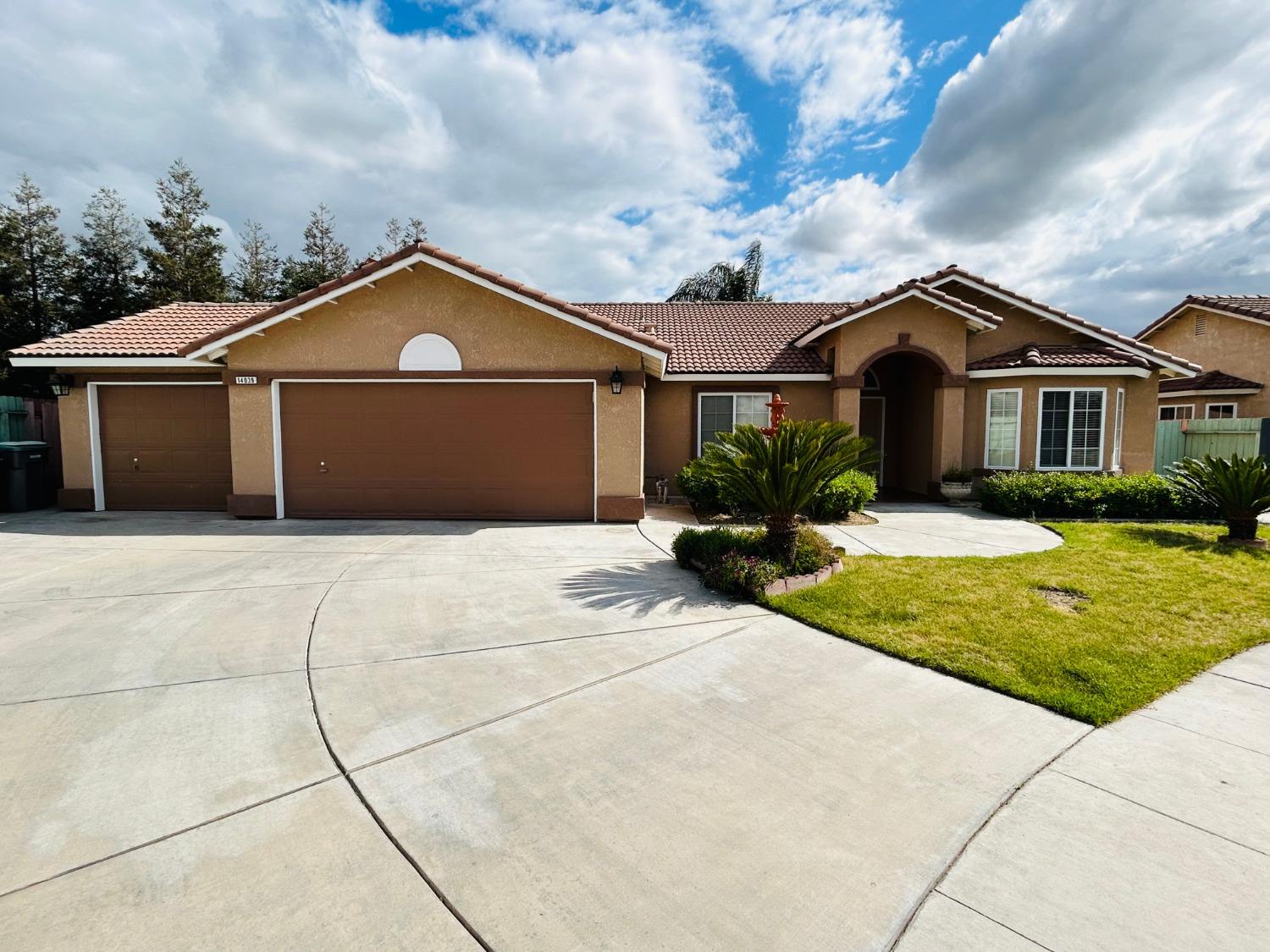 14039 West F Street Kerman, CA 93630 - Photo 2 of 19 a front view of a house with a yard and garage