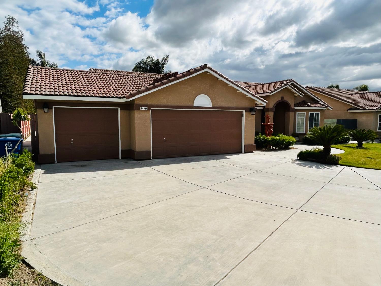 14039 West F Street Kerman, CA 93630 - Photo 4 of 19 a front view of a house with a yard and garage