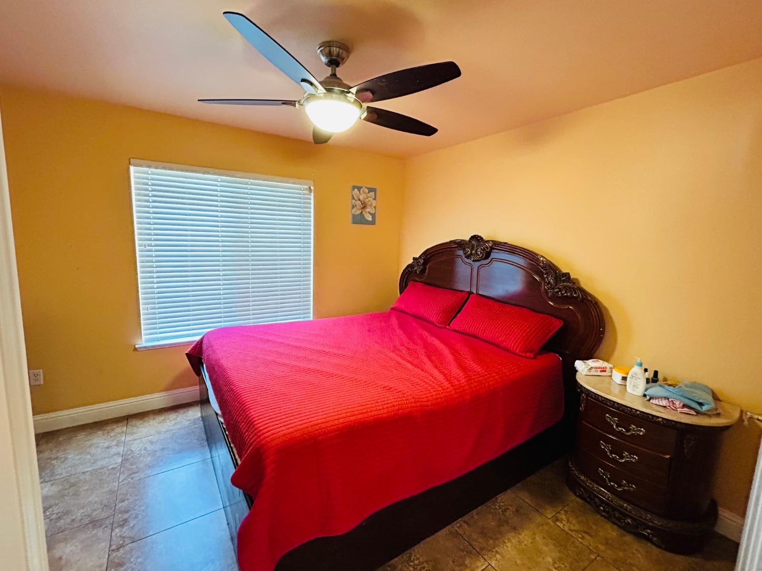 14039 West F Street Kerman, CA 93630 - Photo 9 of 19 a bed sitting in a bedroom next to a window