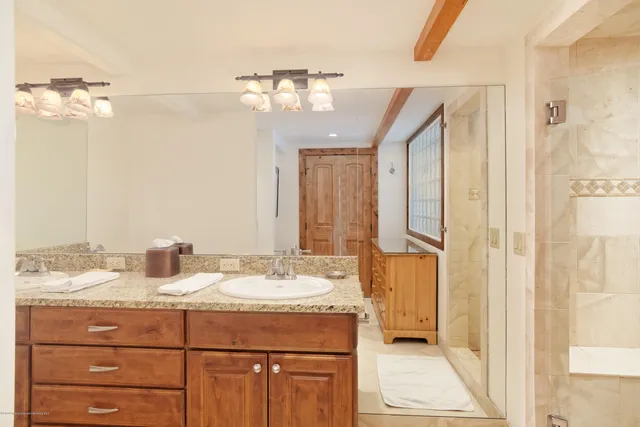 a bathroom with a granite countertop sink a mirror and a shower