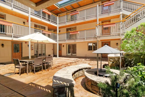 a patio with a dinning table and chairs under an umbrella
