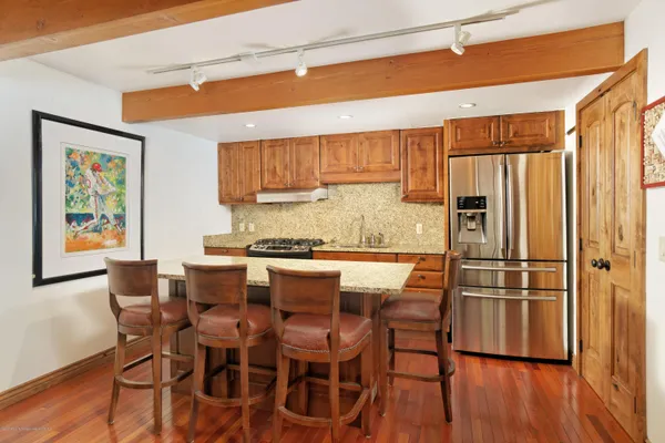 a kitchen with stainless steel appliances granite countertop a refrigerator and wooden cabinets