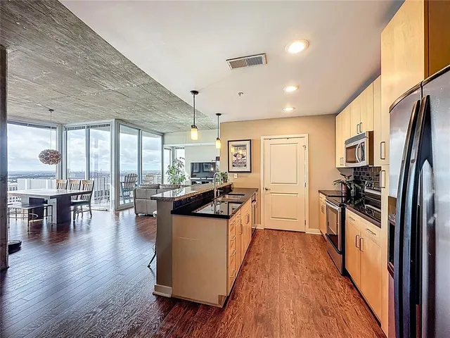 a kitchen with stainless steel appliances granite countertop a sink a stove a refrigerator cabinets and chairs