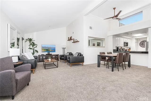 a living room with furniture and a dining table with kitchen appliances