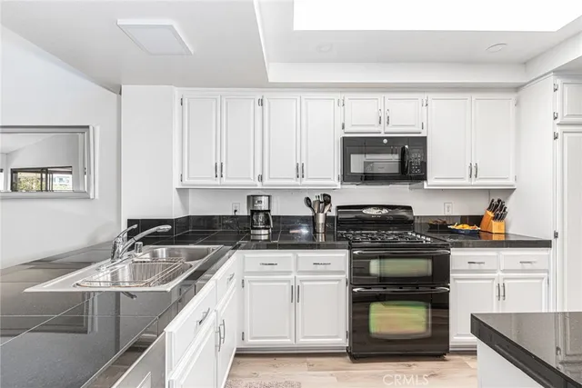 a kitchen with granite countertop a sink a stove and cabinets