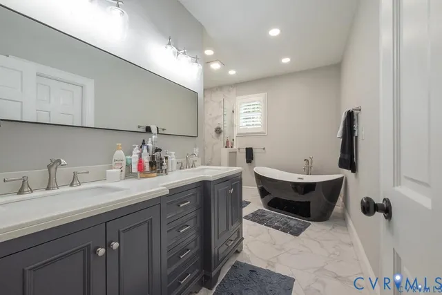 a spacious bathroom with a double vanity sink mirror and bathtub