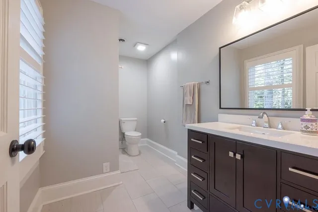 a spacious bathroom with a granite countertop sink toilet and mirror