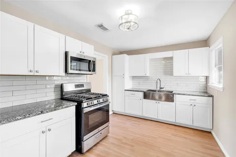 a kitchen with granite countertop white cabinets and appliances