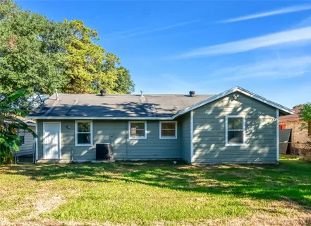 a view of a house with a yard plants and large tree