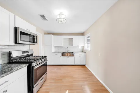 a kitchen with stainless steel appliances a stove top oven a sink a microwave and cabinets