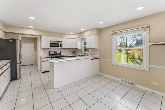 a kitchen with white cabinets a sink a window and stainless steel appliances