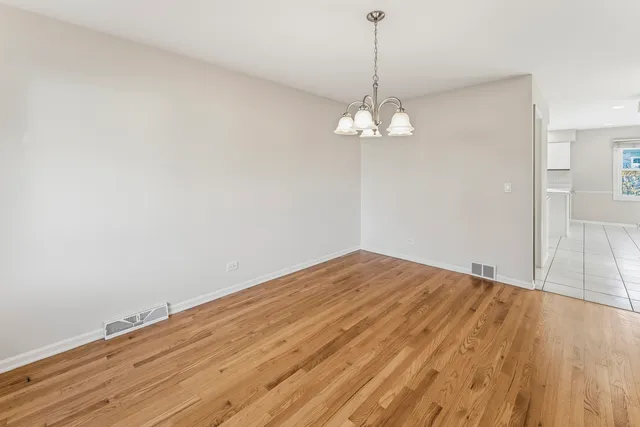 a view of empty room with wooden floor and chandelier
