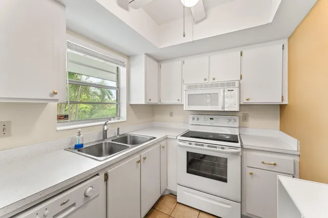 a kitchen with white cabinets appliances and a window