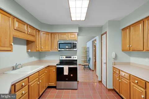 a kitchen with stainless steel appliances a stove sink refrigerator and cabinets