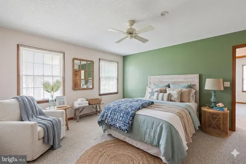 a bedroom with a bed couches and windows