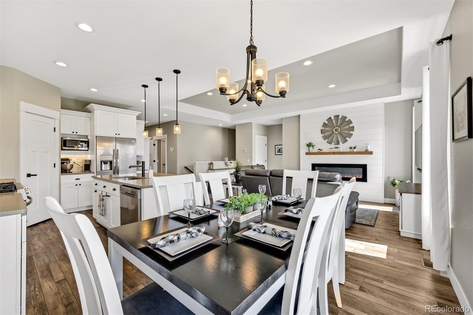 1122 Johnson Street Wiggins, CO 80654 - Photo 22 of 37 a view of a dining room with furniture a kitchen and chandelier