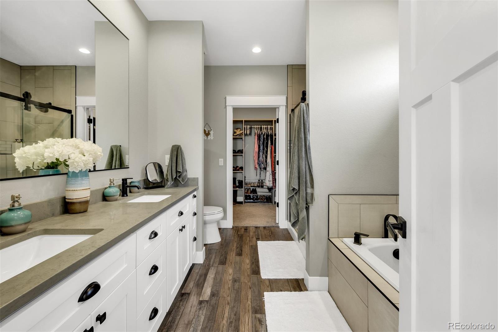 1122 Johnson Street Wiggins, CO 80654 - Photo 25 of 37 a large bathroom with a tub double vanity sink and mirror