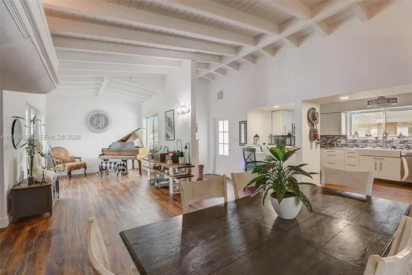 a living room with couches and kitchen view with wooden floor