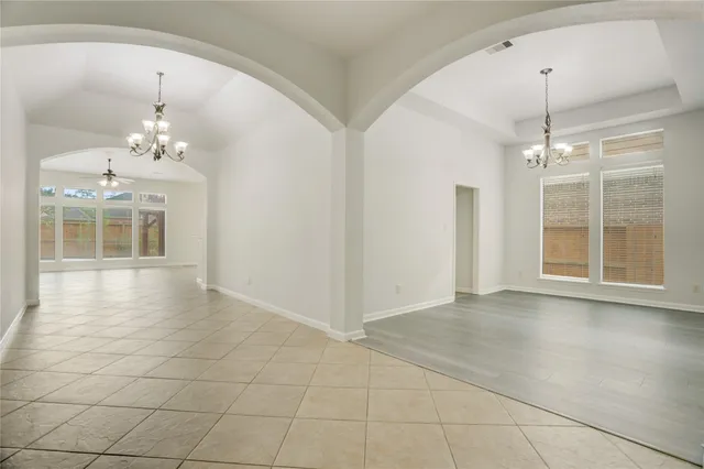 an empty room with chandelier and windows