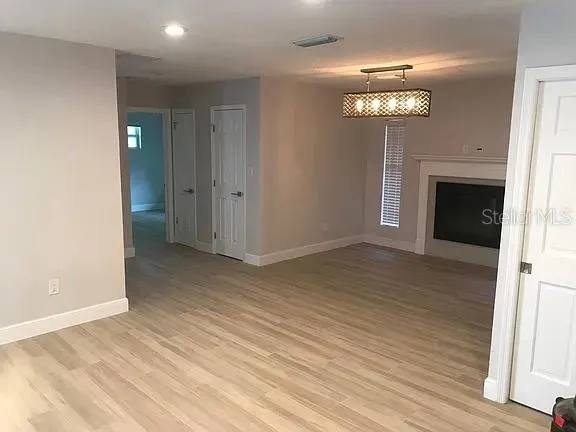 a view of a livingroom with a fireplace a chandelier and wooden floor