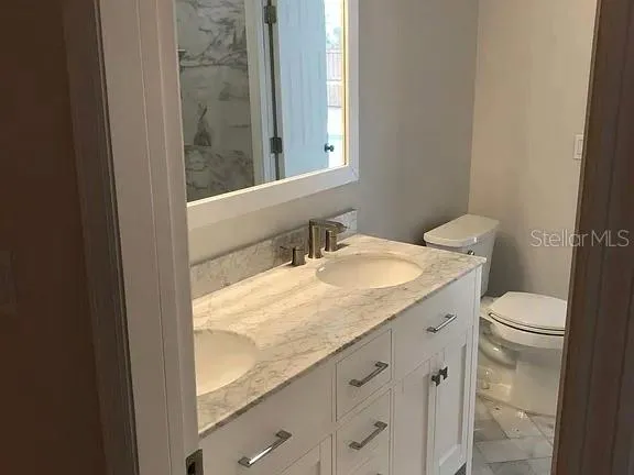 a bathroom with a granite countertop sink toilet and mirror
